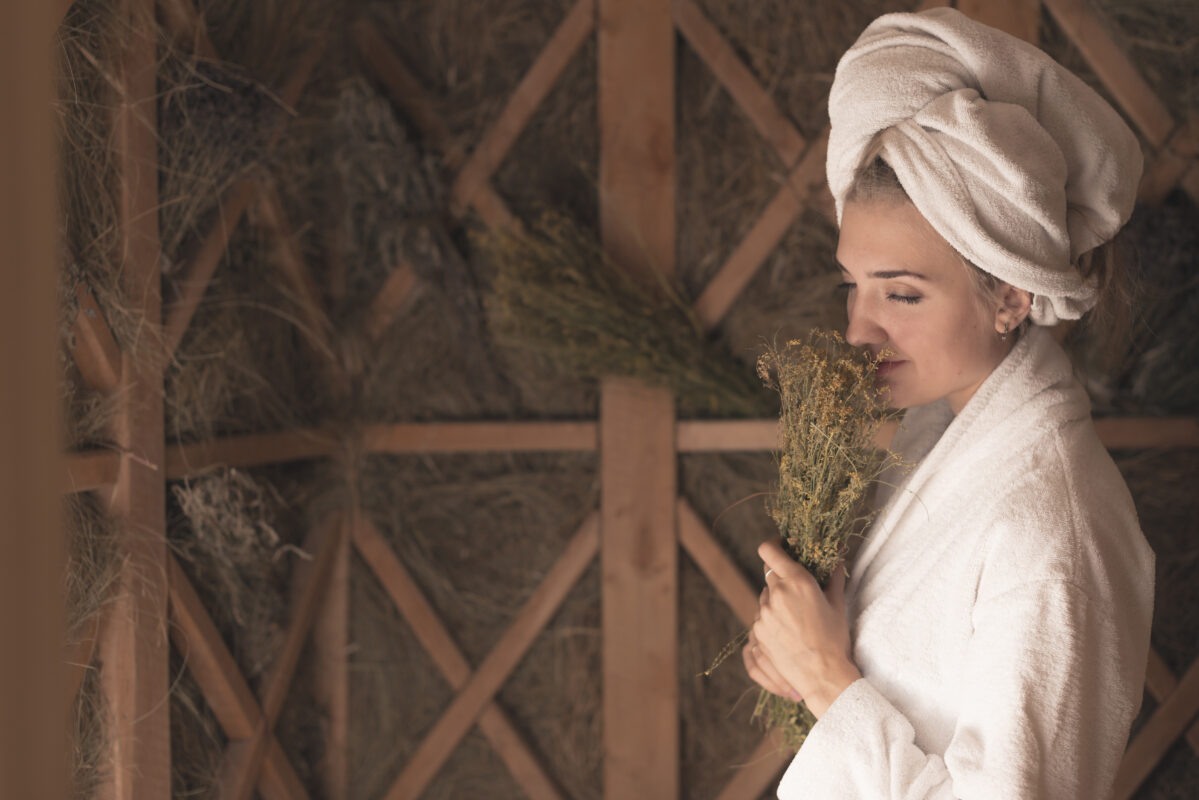 young-woman-smelling-herb-flowers-standing-sauna